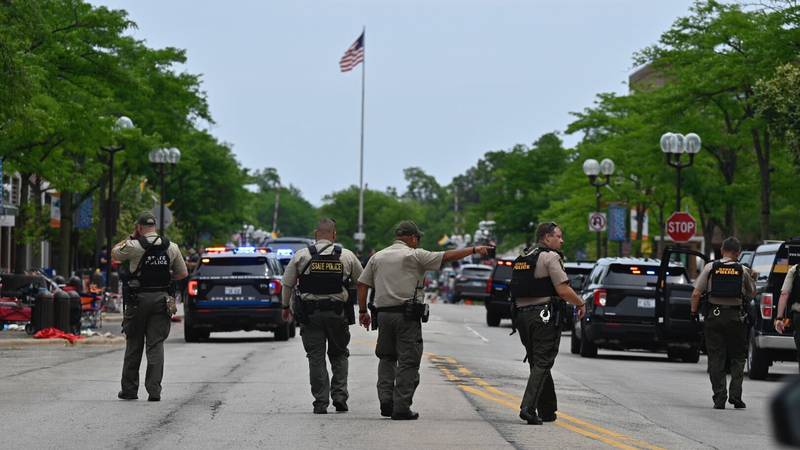 Police search the downtown area of the Chicago suburb of Highland Park, Ill., after a mass...