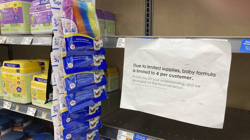 A sign telling consumers of limits on the purchase of baby formula hangs on the edge of an...