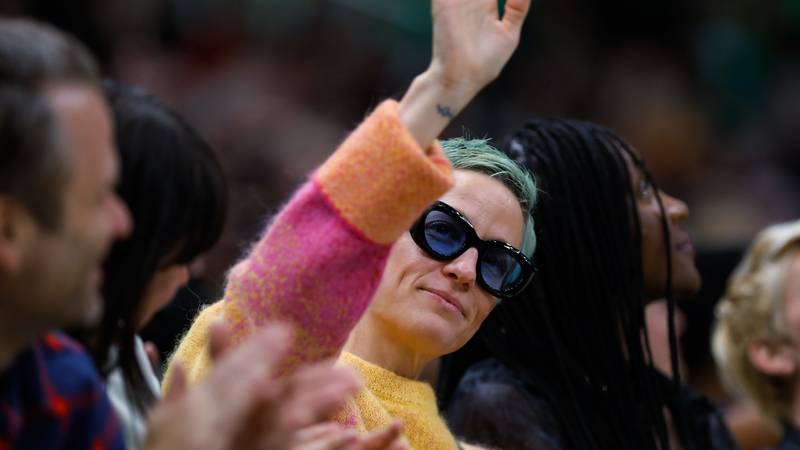 Soccer player Megan Rapinoe waves to the crowd during the second quarter of a WNBA basketball...