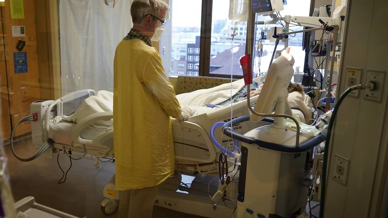 Steve Grove, a chaplain at Hennepin County Medical Center, prays in a COVID-19 patient's room,...