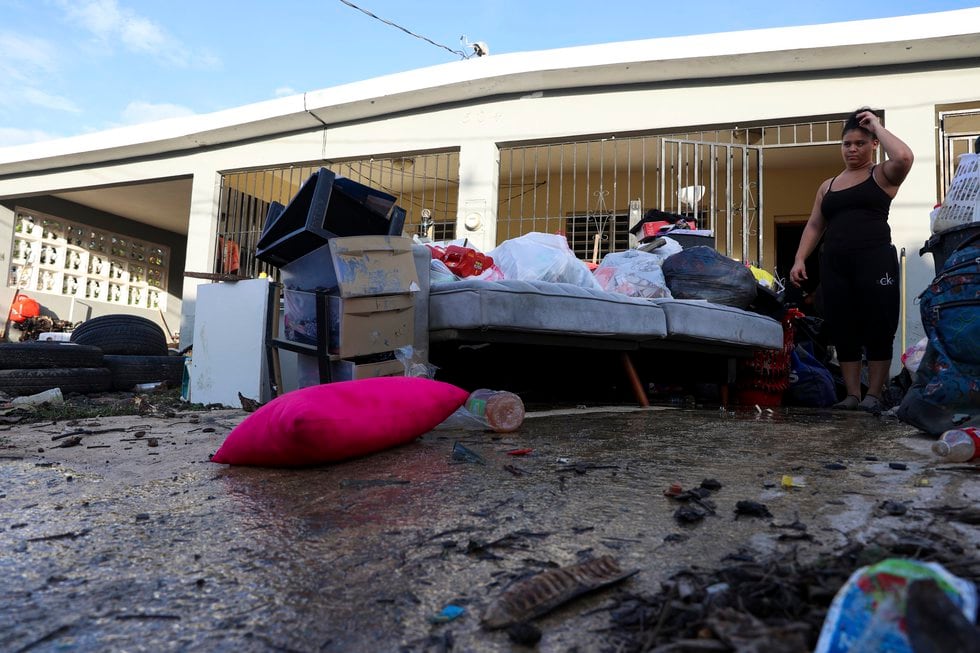 A woman looks at her water-damaged belongings after flooding caused by Hurricane Fiona tore...