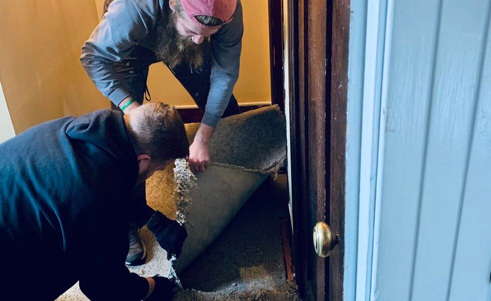Two local pastors volunteered to tear out damaged flooring after a septic clog flooded "Place...