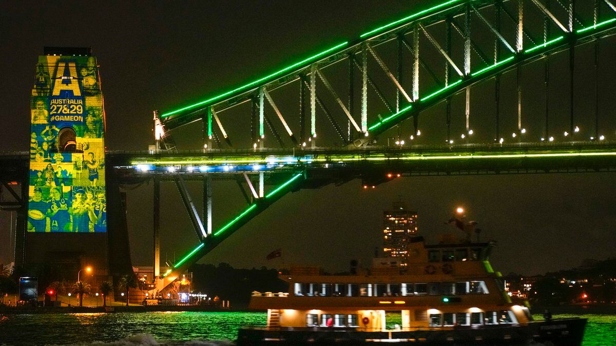 A Sydney ferry sails past the illuminated pylon of the Sydney Harbour Bridge ahead of the final...