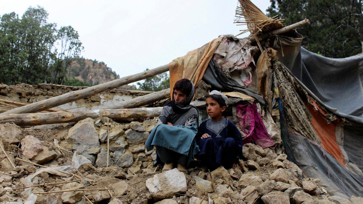 Afghan boys sit near their damaged house that was destroyed in an earthquake in the Spera...