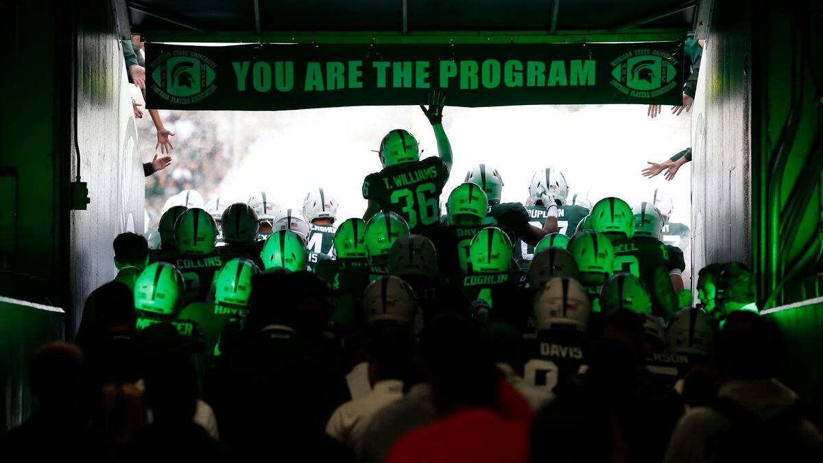 FILE - Michigan State players run through the tunnel to take the field before an NCAA college...