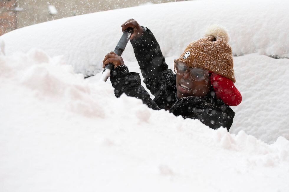 Zaria Black, 24, from Buffalo, clears off her car as snow falls Friday, Nov. 18, 2022, in...