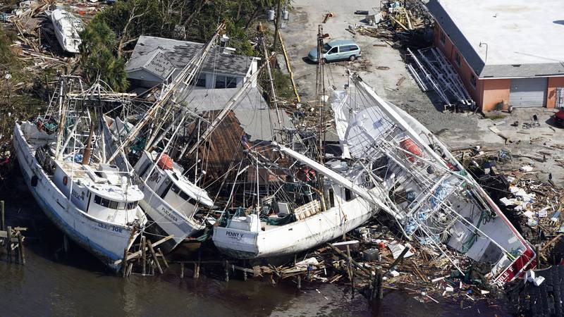In this aerial photo, damaged boats and debris are stacked along the shore in the aftermath of...