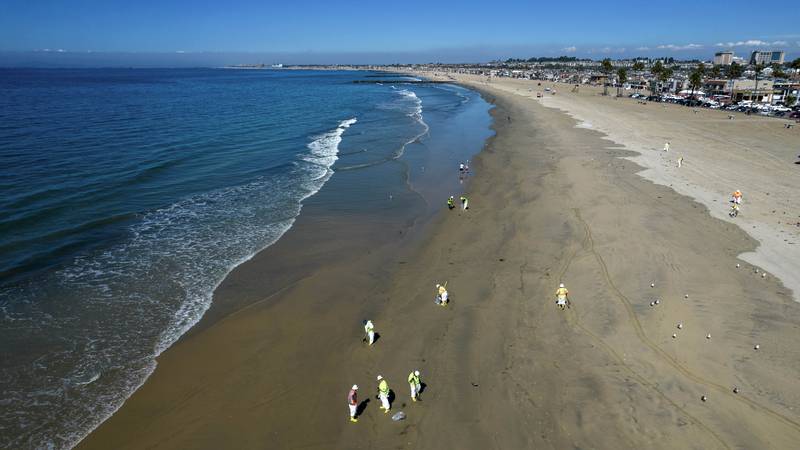 Workers clean oil from the sand south of the pier in Newport Beach, Calif., Tuesday, Oct. 5,...