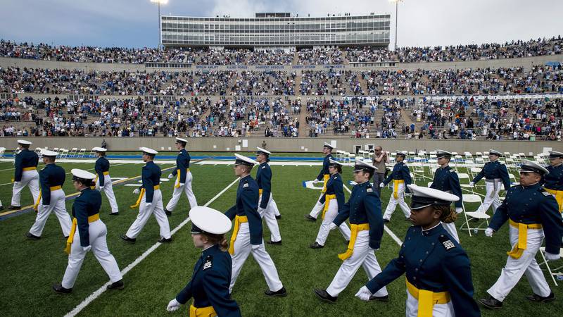 FILE - Air Force Academy cadets make their way to their seats as family and friends cheer from...