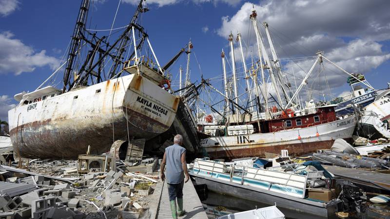 Bruce Hickey, 70, walks along the waterfront littered with debris, including shrimp boats, in...