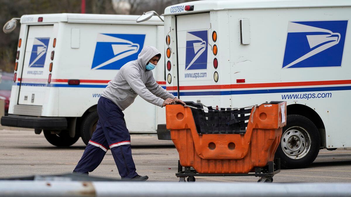 FILE - A United States Postal Service employee works outside a post office in Wheeling, Ill.,...