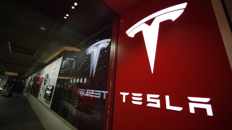 FILE - This photo shows a sign bearing the company logo outside a Tesla store Feb. 9, 2019 in...