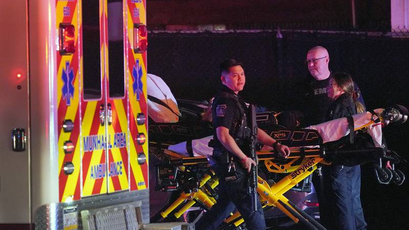 A law enforcement officer walks past an EMS crew on the scene at Kennywood Park, an amusement...