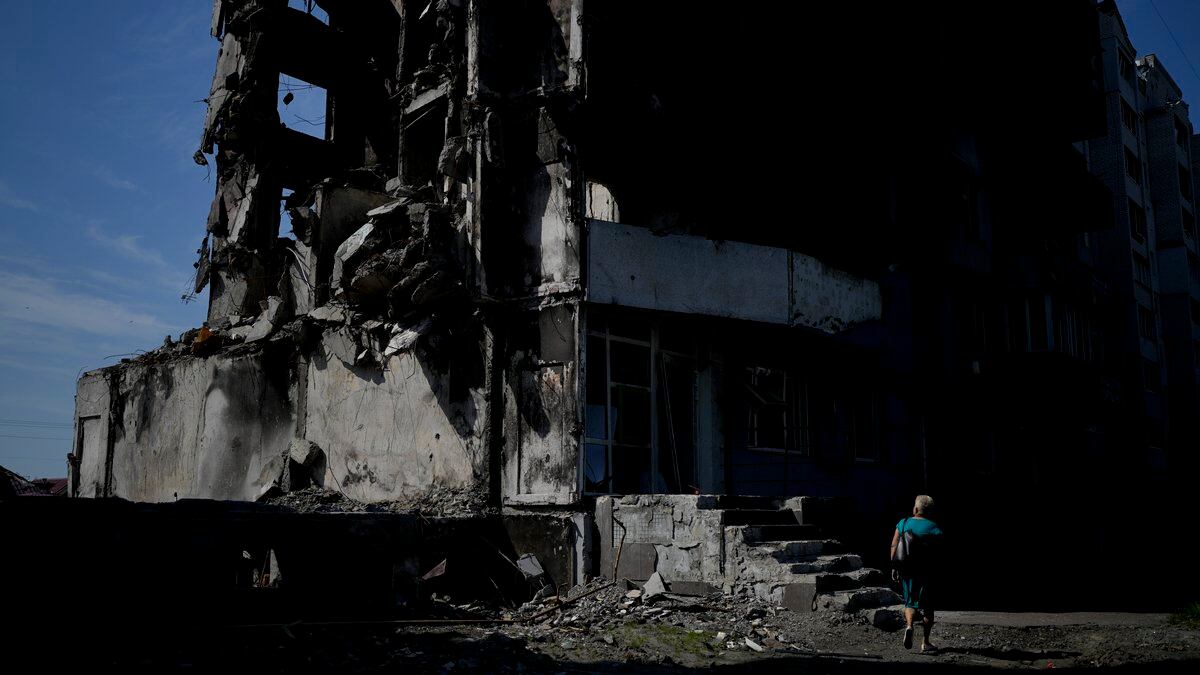 FILE - A woman walks past a building destroyed in Russian shelling in Borodyanka, on the...