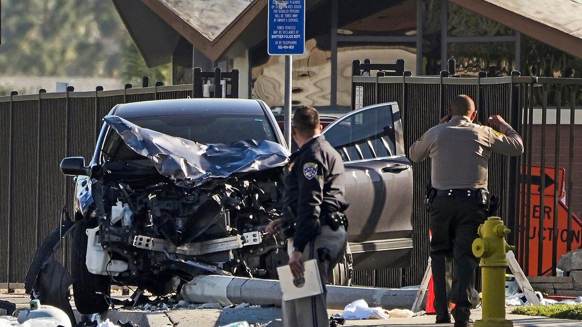 FILE - Two investigators stand next to a mangled SUV that struck Los Angeles County sheriff's...